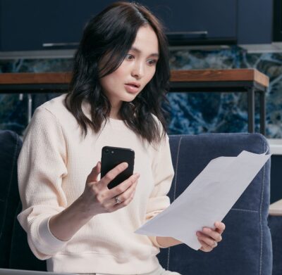 person acting shocked about an invoice with a smartphone in her hand